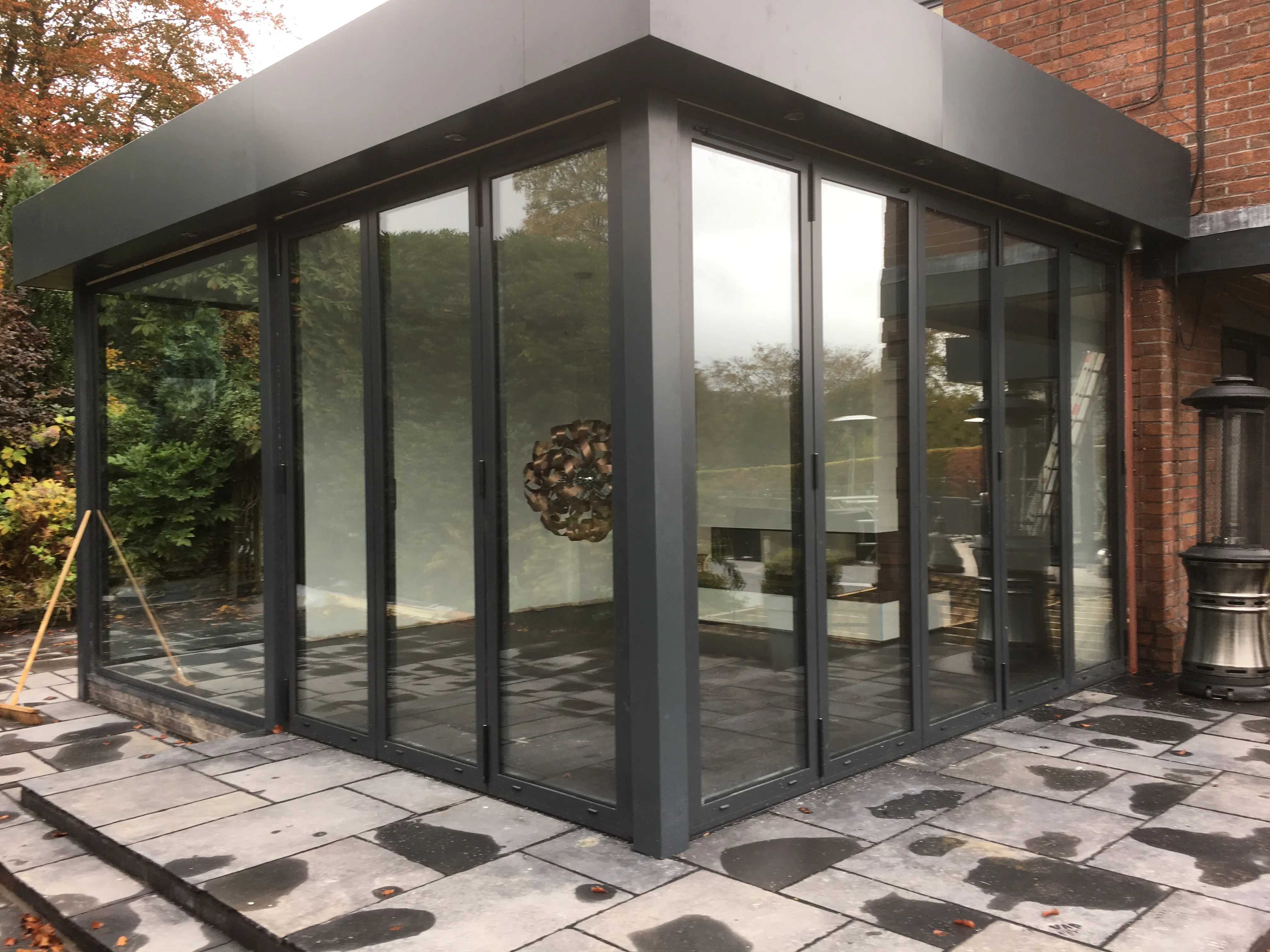Corner garden room: Slim-frame corner glazing opening onto porcelain paving.