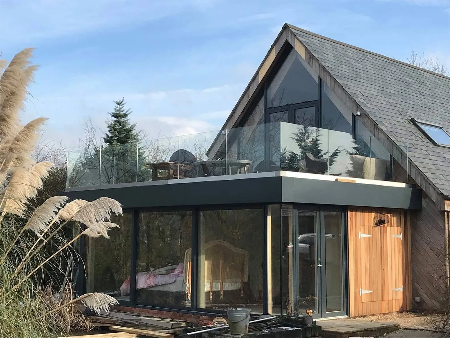Gable extension & balcony: Rendered gable with full-height glazing and a glass-balustrade deck.