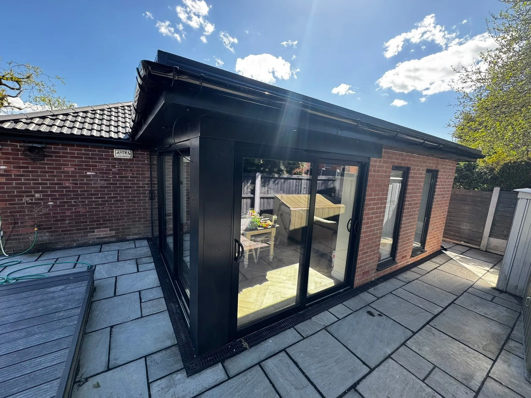 Timber-clad garden room: External building with sliding glazing and paved surround.