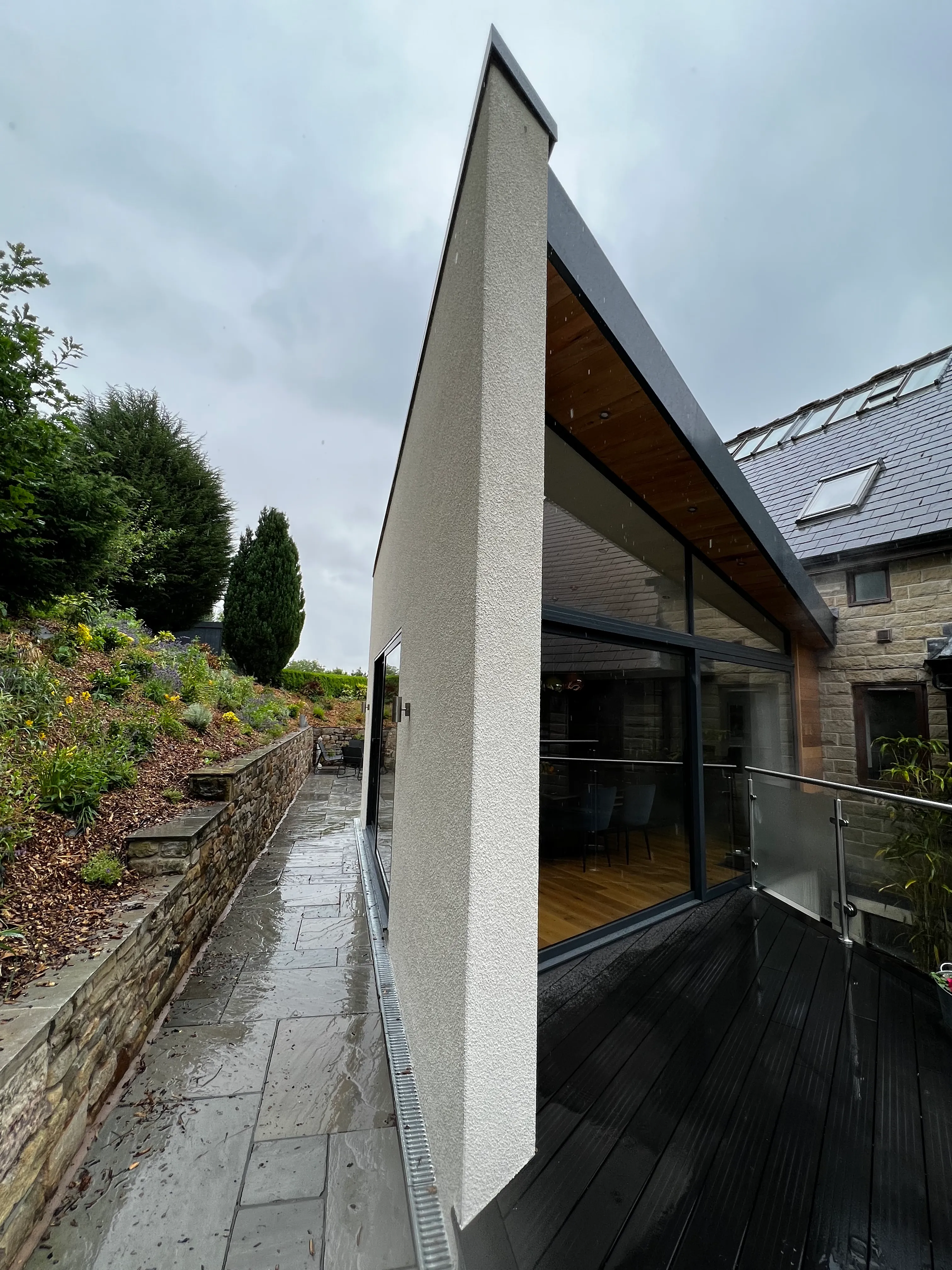 A white render fin and cedar soffit on a new extension beside the stone house